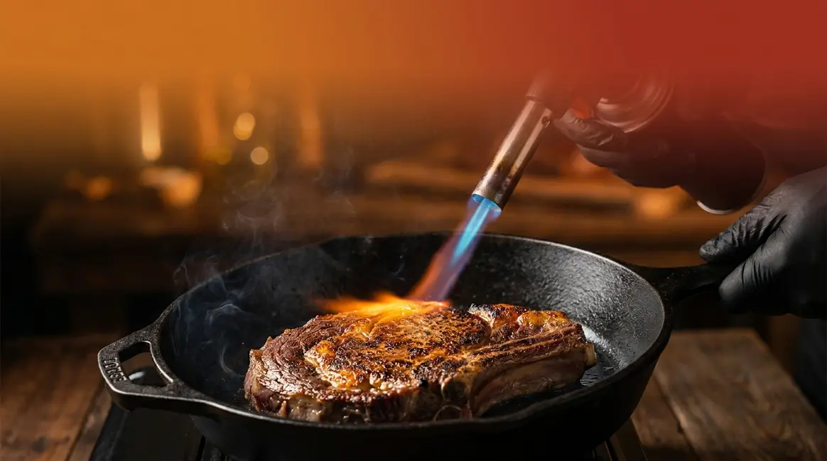 Best sous vide torch searing a ribeye steak with a blue propane flame on cast iron